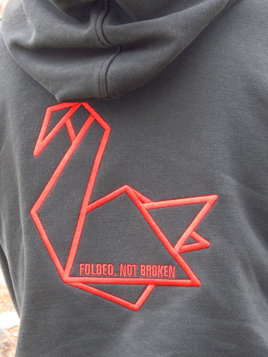 Red origami swan embroidered on a grey hoodie with the words Folded, not broken